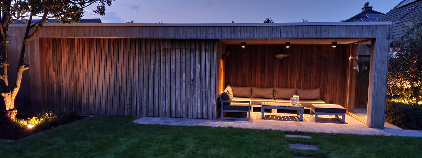 Modern bijgebouw met terrasoverkapping in padouk met buitenverlichting Oost Vlaanderen
